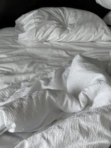someone has clearly gotten out of a bed. Pillow and disturbed sheets